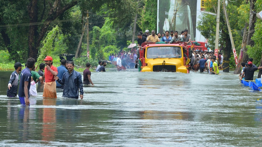 A truck carries people past a flooded road
