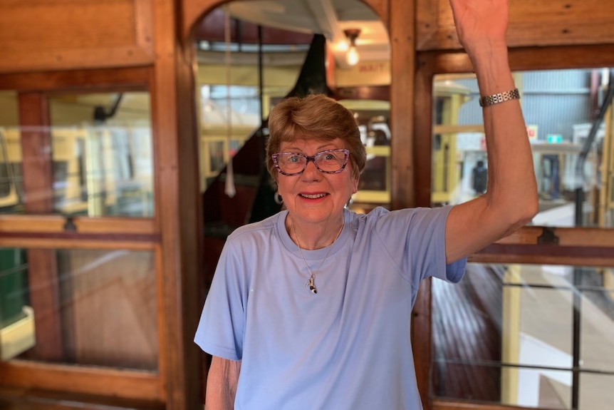 Judy Spinks smiles as she stands on a tram.