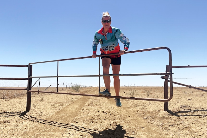 Woman swings on cattle gate in outback Queensland