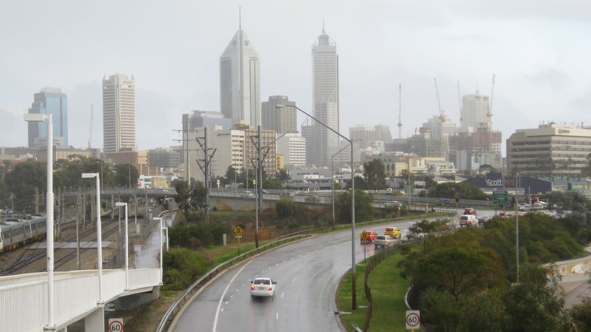 Rain falls over Perth's CBD as cars exit the Graham Farmer Freeway.