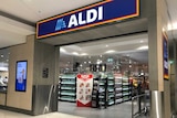 An Aldi storefront is seen with white and rose wine bottles just past the entrance. A Super Savers sign sits in the entrance.