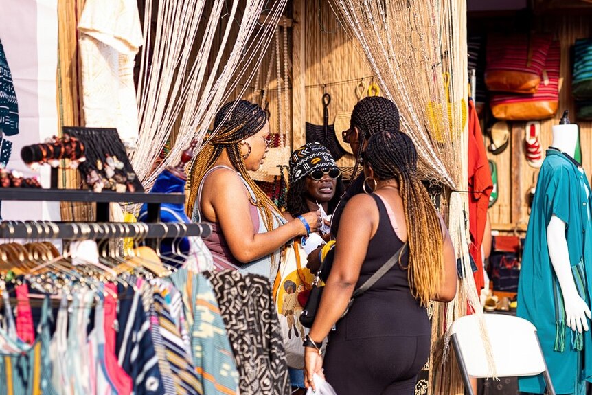 Two people with long braids shopping with clothing, shoes and accessories on display
