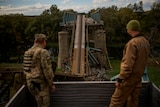 Ukrainian soldiers remove metal structure pieces as they work on a bridge damaged during fighting.