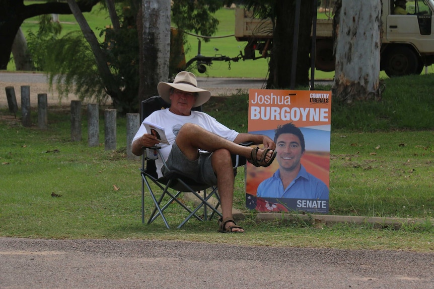 Guy sitting on a chair giving out how to vote cards.