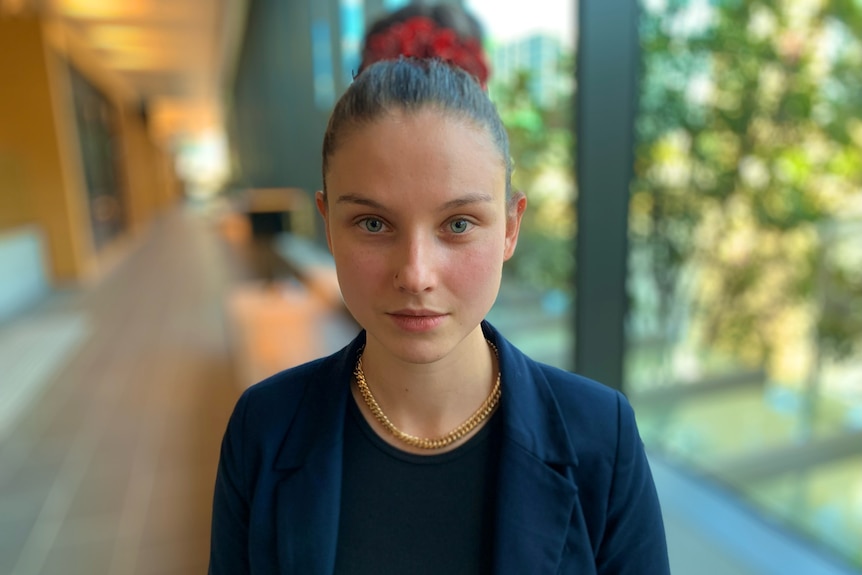 ANZ senior economist Adelaide Timbrell standing in a hallway with trees outside the window.