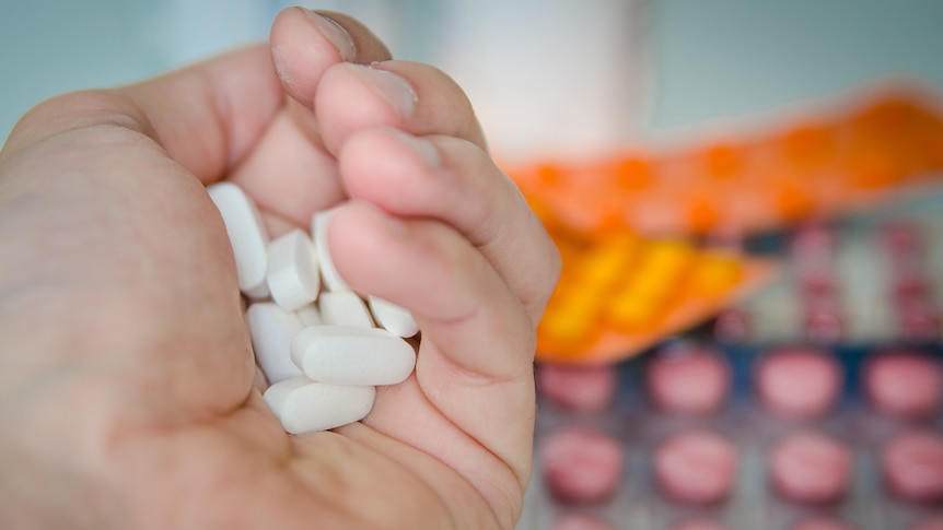 A hand holding tablets.