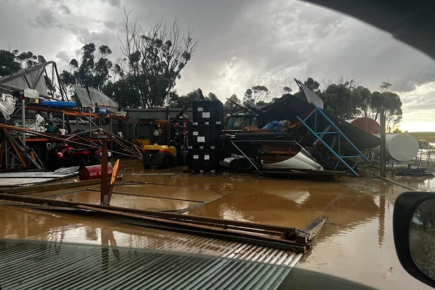 A shed that has collapsed, with floodwaters in the foreground.