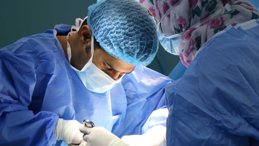 Two surgeons operating in scrubs.