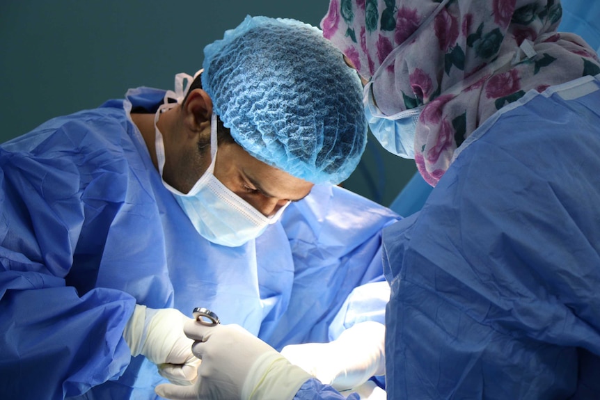 Two surgeons operating in scrubs.