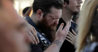 Man cries into his hand while being comforted by a friend at a vigil following the Las Vegas mass shooting.