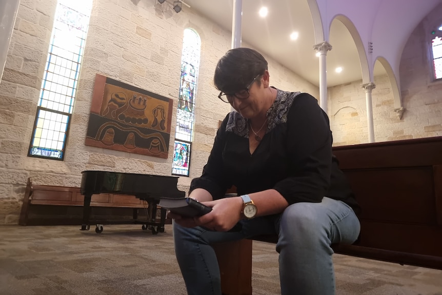 Woman sitting down in a church holding the bible. 
