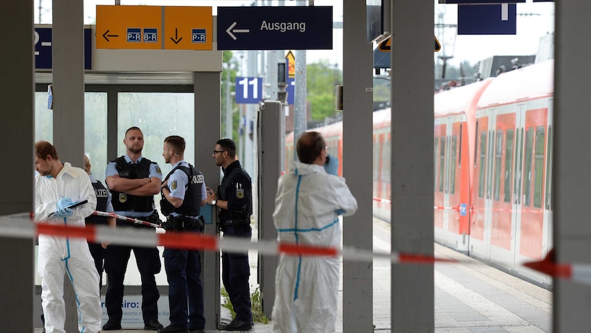 Police and forensice experts stand on station platform.