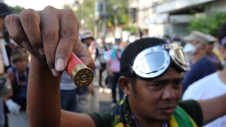 An anti-government protester displays an empty shotgun shell allegedly found during a demonstration in Bangkok.