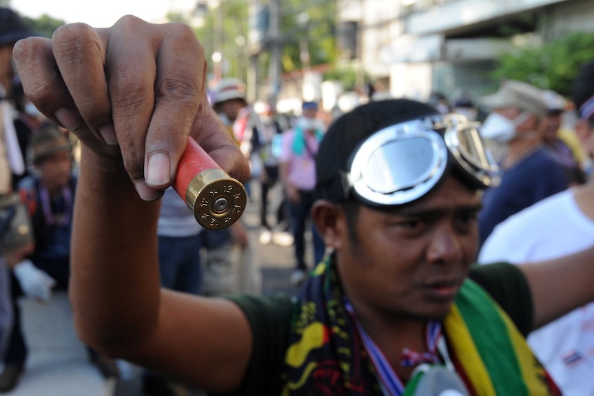 An anti-government protester displays an empty shotgun shell allegedly found during a demonstration in Bangkok.