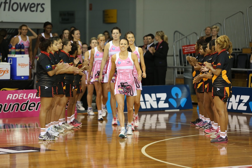 Two lines of SAASTA netball players create a walkway for the Thunderbirds to enter the court