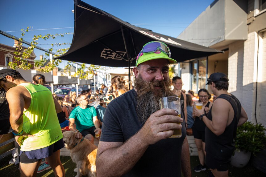 A man holds a beer in front of a crowd of people.