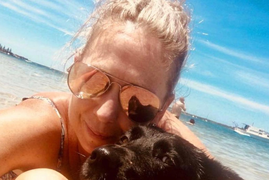 Lisa Davey on a beach with her dog.