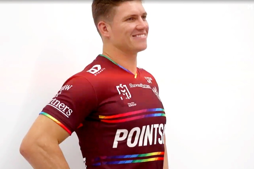 Seorang pria berdiri dan tersenyum dengan jersey warna-warni 