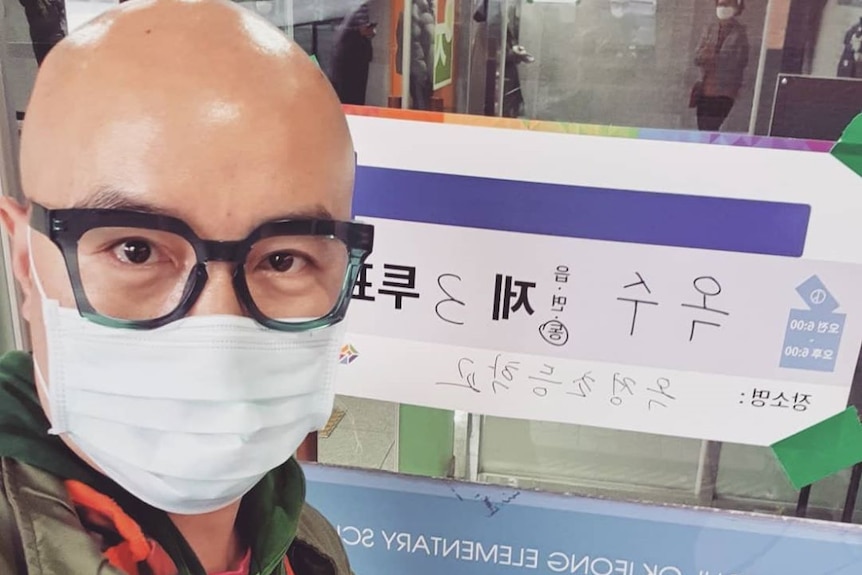 Hong Seok Cheon in a medical face mask taking a selfie