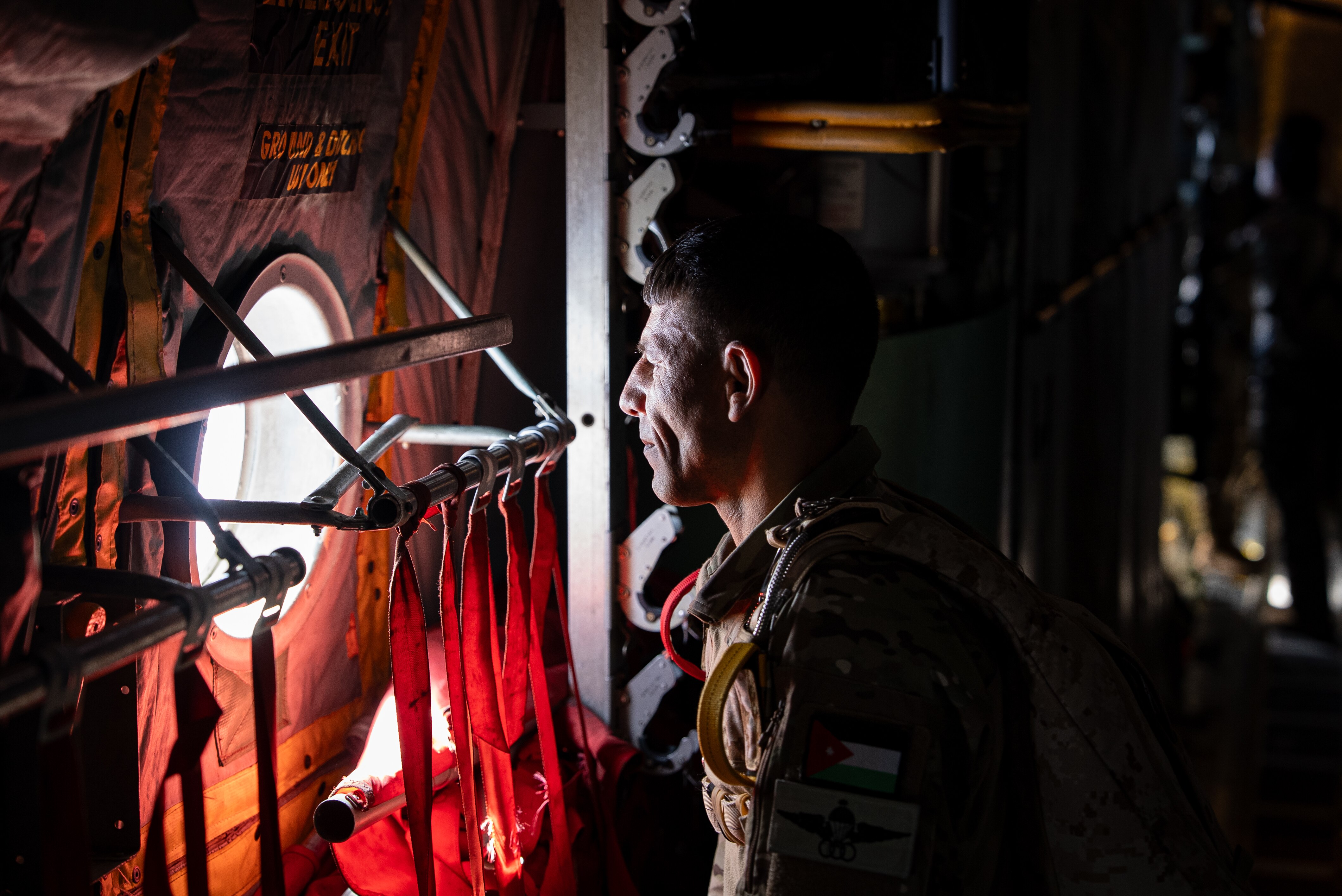 A soldier looks out the window of a military aircraft.