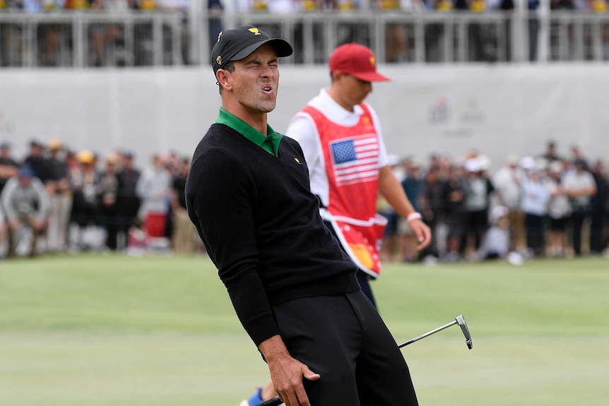 Adam Scott crouches and leans back while grimacing after missing a putt