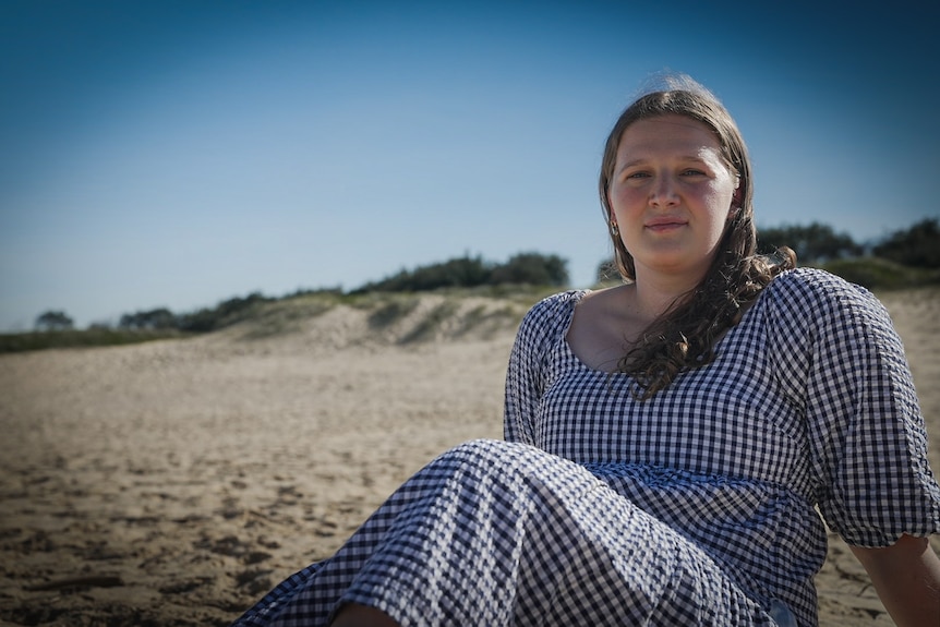 Former retail worker Hannah sits on the beach
