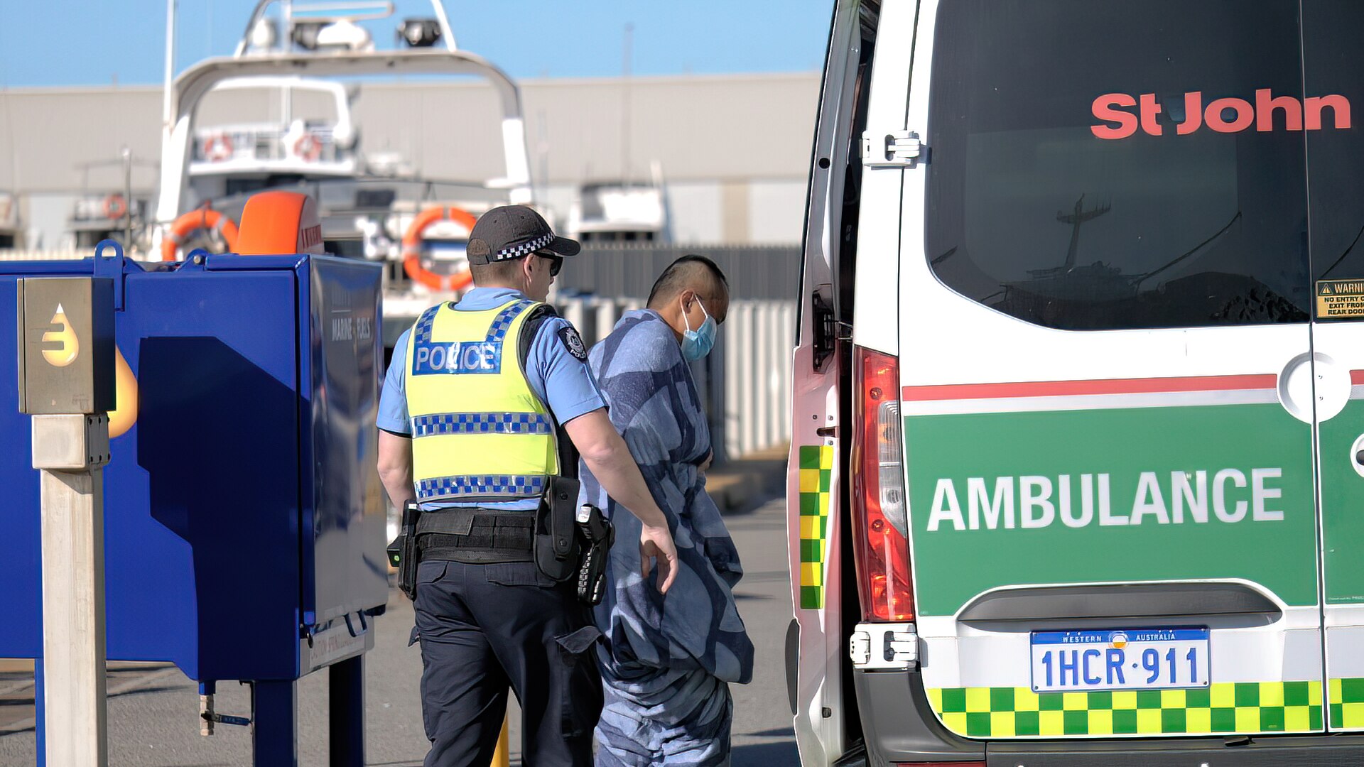 Man wrapped in blanket sets onto ambulance 
