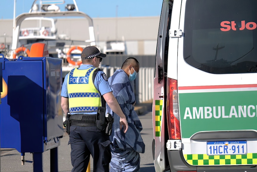 Un homme enveloppé dans une couverture s'installe dans une ambulance 