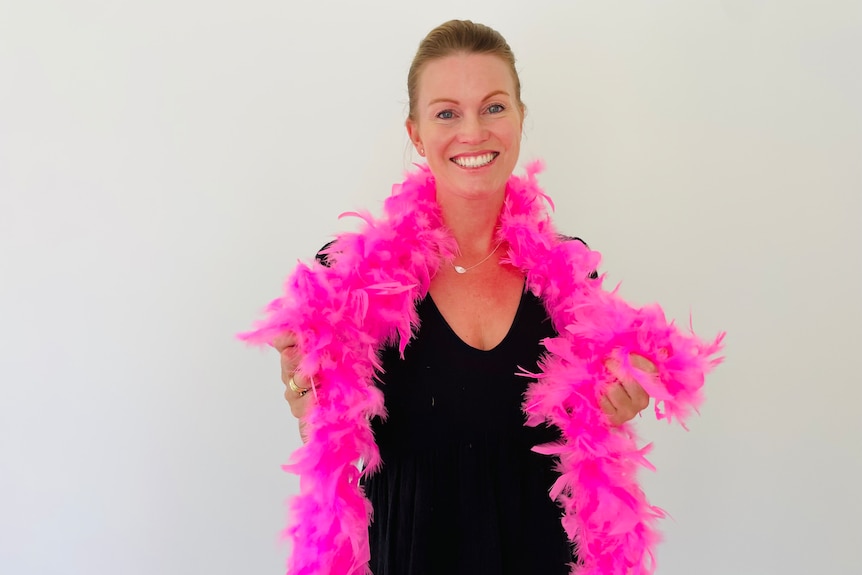 Woman smiles while wearing pink feather boa