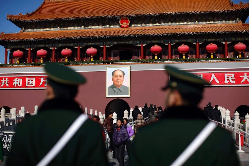 Guards stand in front of a portrait of late chairman Mao Zedong