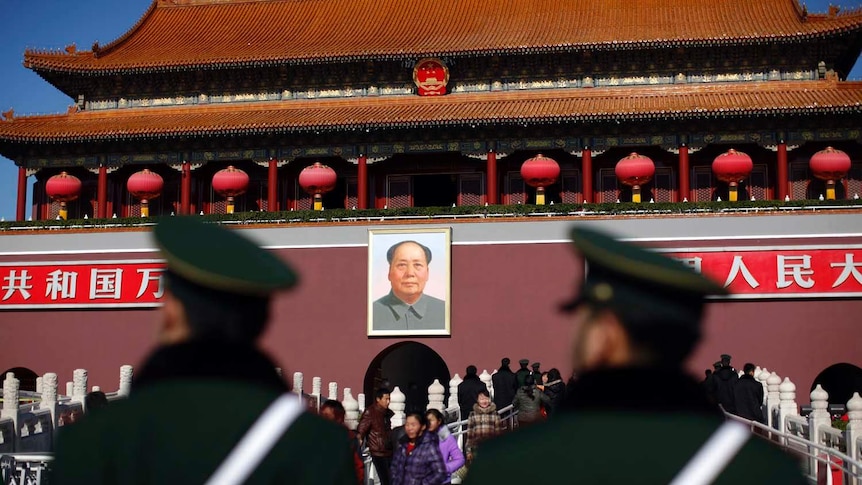 Guards stand in front of a portrait of late chairman Mao Zedong