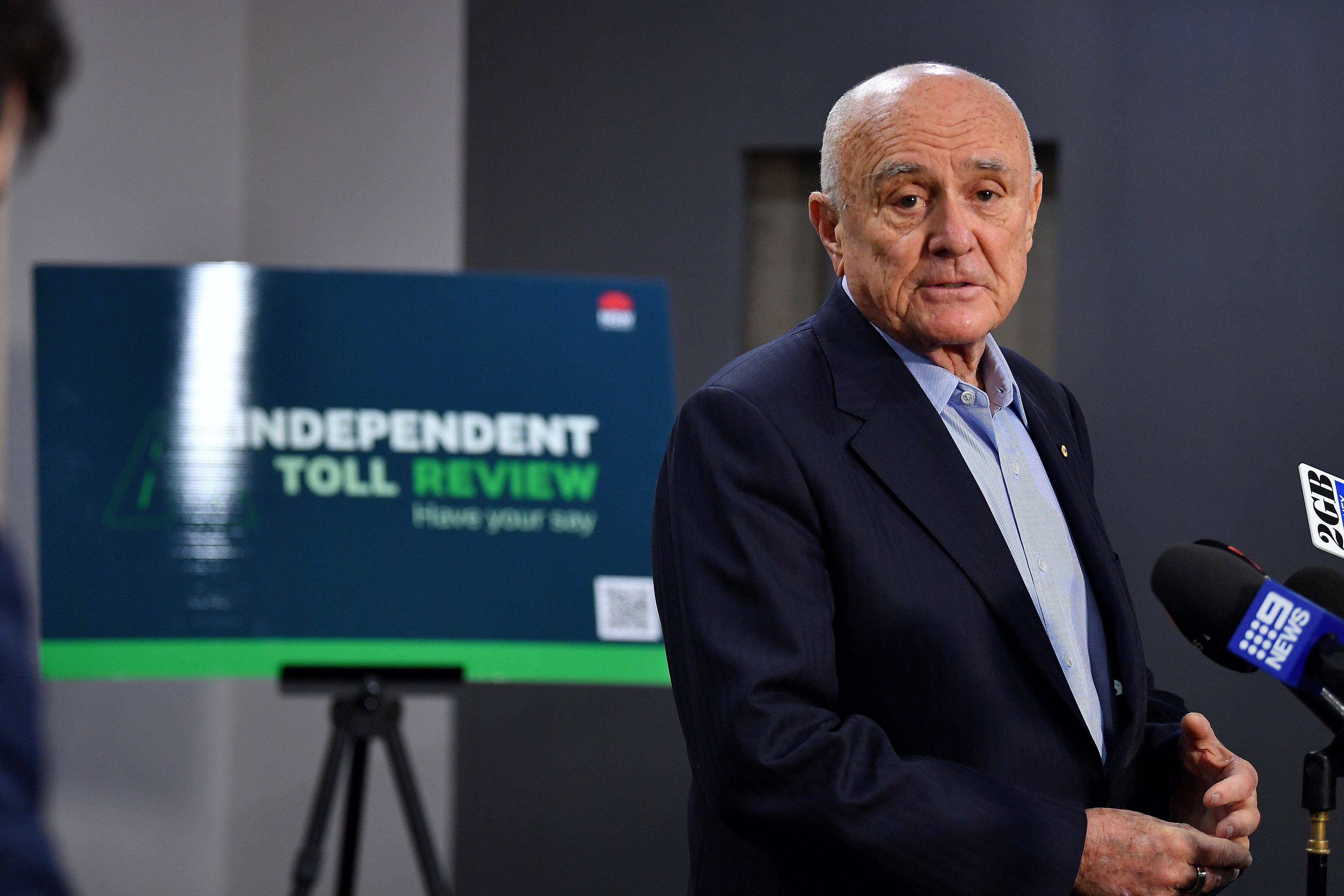 Professor Allan Fels standing in front of a sign that reads independent toll review at a press conference