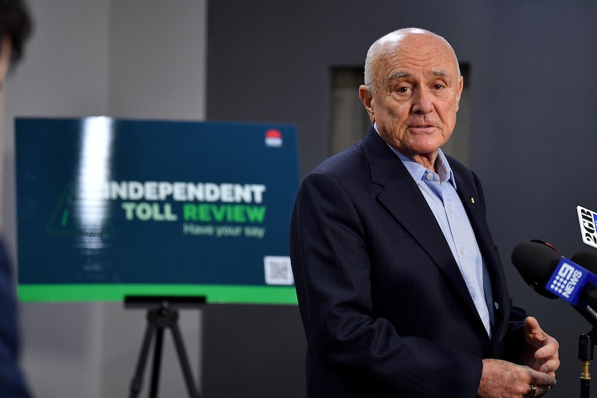 Professor Allan Fels standing in front of a sign that reads independent toll review at a press conference