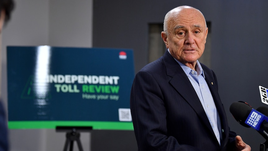 Professor Allan Fels standing in front of a sign that reads independent toll review at a press conference