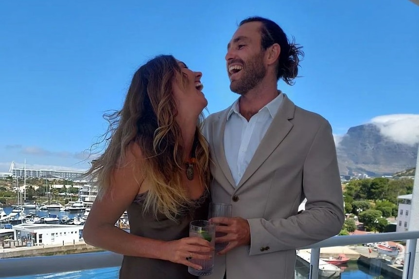 A man laughs while looking at a woman on a balcony.