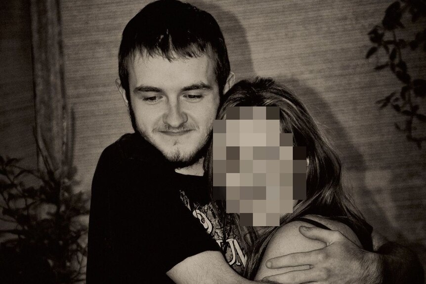 A young man with short dark hair hugs a female who has her face pixelated