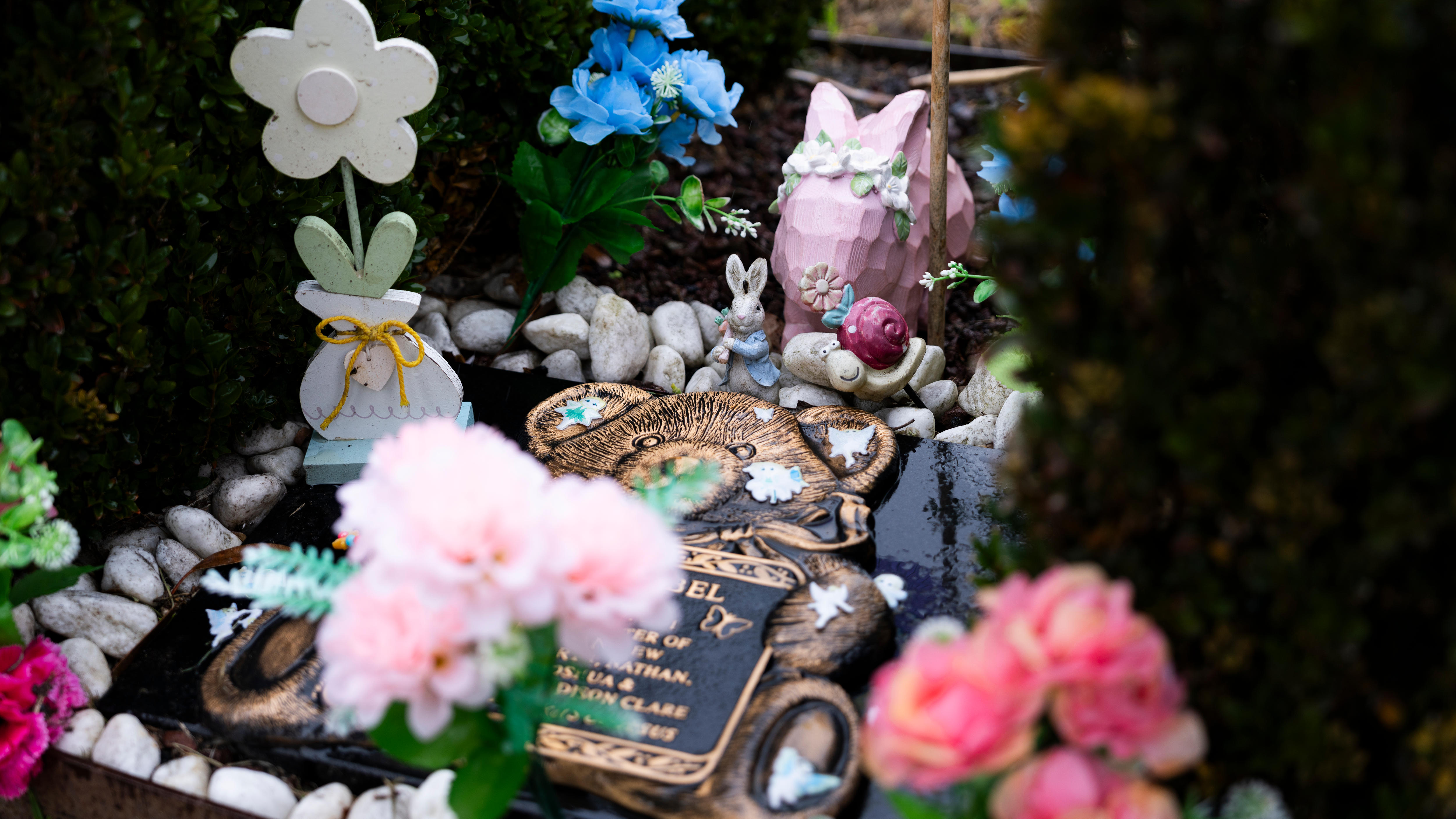 A child's grave adorned with flowers, bunnies and other sweet trinkets