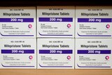 Boxes of Mifeprisone tablets are stacked on top of each other on a shelf