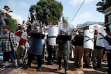 White nationalists hold plastic shields and carry black and white flags.