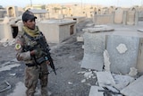 An Iraqi special forces soldier stands in a Christian cemetery inside a church compound damaged by Islamic States fighters