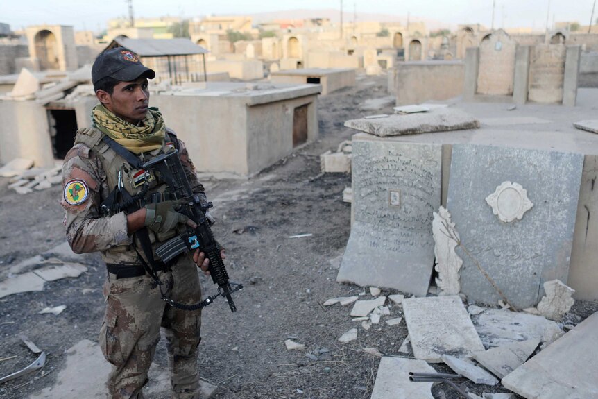 An Iraqi special forces soldier stands in a Christian cemetery inside a church compound damaged by Islamic States fighters