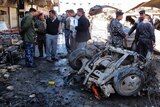Iraqi policemen in the central town of Hilla inspect the site of a car bomb that killed two people.