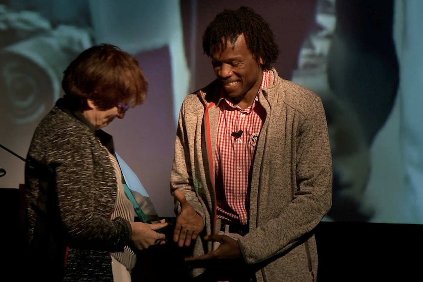 A woman hands a glass award to a man.
