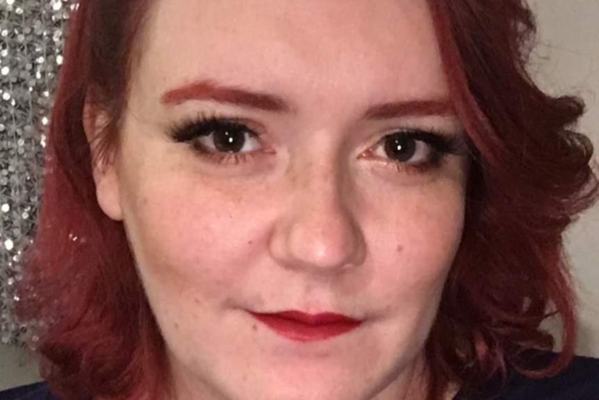 A selfie of a young woman with dyed red eyebrows and hair.