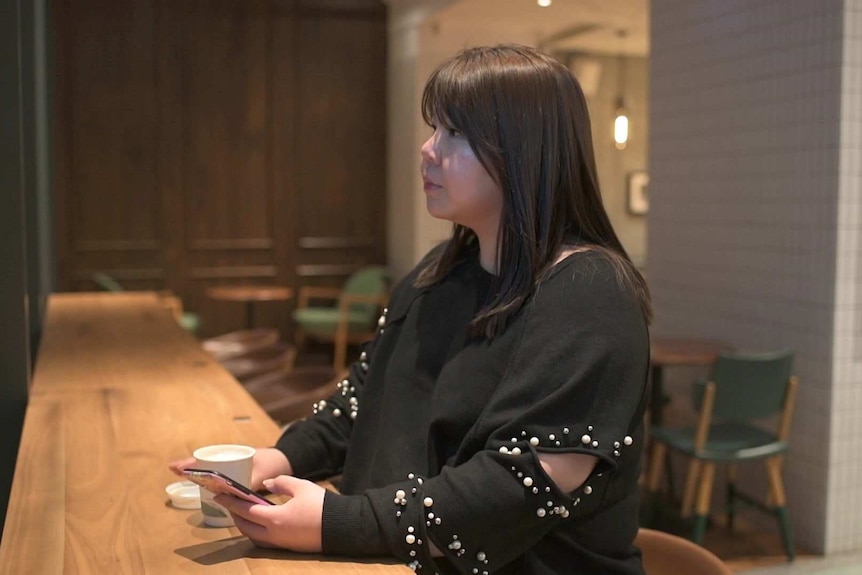 A woman holds a cup of coffee in a cafe.