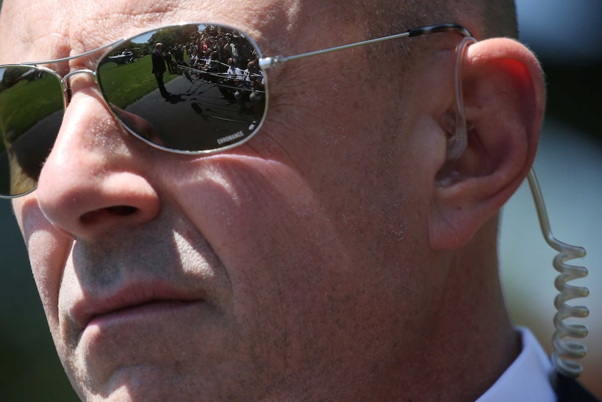 A U.S. Secret Service Agent keeps watch as U.S. President Donald Trump talks to reporters