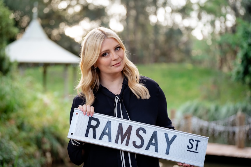 Mischa Barton holding a ramsey street sign