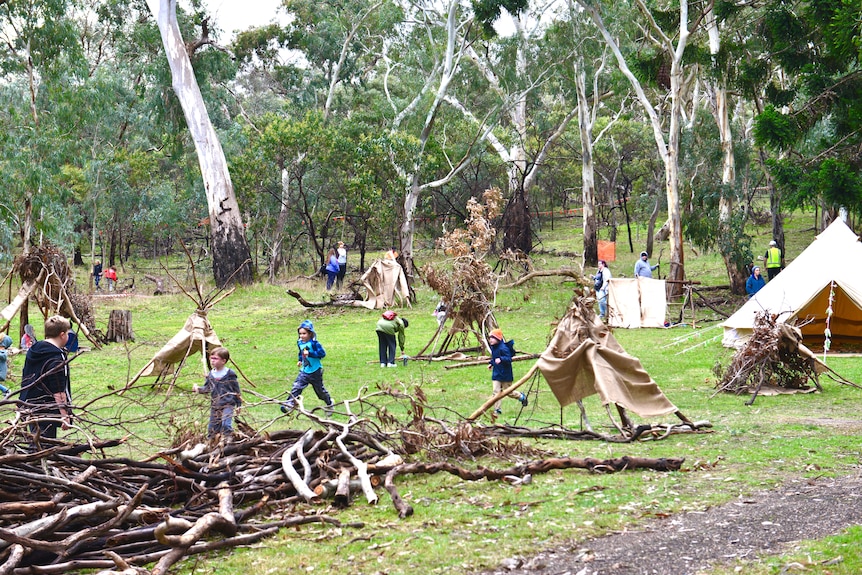 Children playing with branches and materials to build cubby houses.