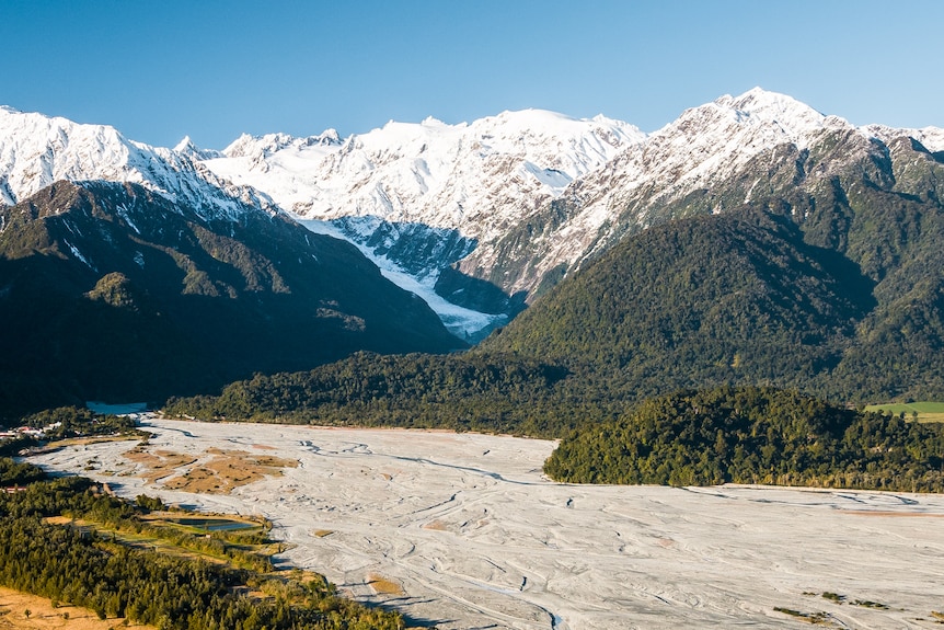 A wide shot shows the glacier in the background