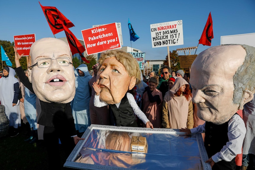 Climate protesters wearing masks of German politicians